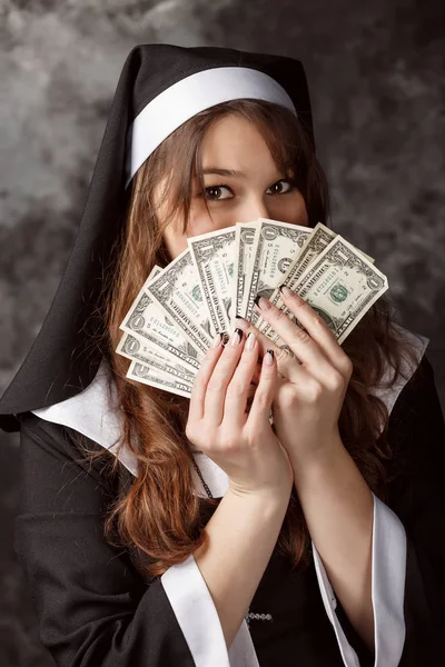 Nahaufnahme attraktive Nonne mit dunklen Haaren hält einen Dollarschein und bedeckt sein Gesicht sie — Stockfoto