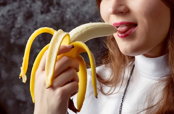 Primo piano di una suora sexy mangia banana su uno sfondo scuro. Donna mangia una banana — Foto Stock