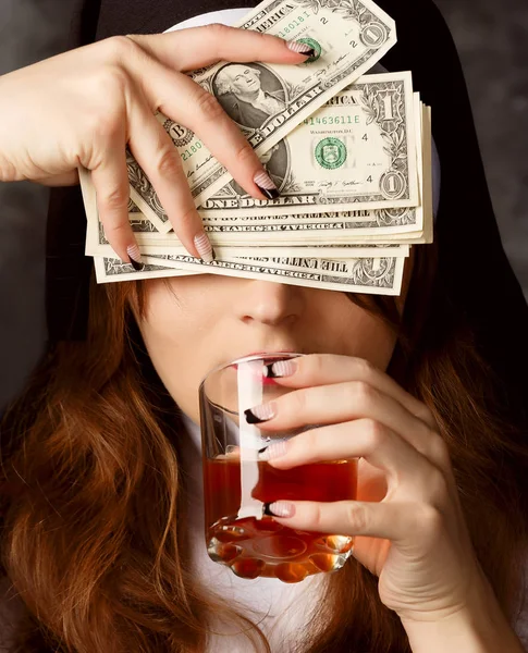 Nonne mit Dollarscheinen und Glas mit Alkohol auf dunklem Hintergrund. Frau Hand mit Schnitten geschlossenen Augen und trank Alkohol — Stockfoto