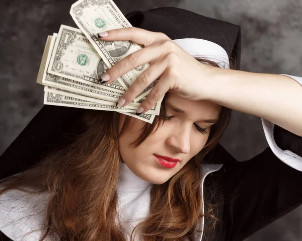 Porträt einer Nonne mit Dollarscheinen und einem Glas Alkohol auf dunklem Hintergrund — Stockfoto