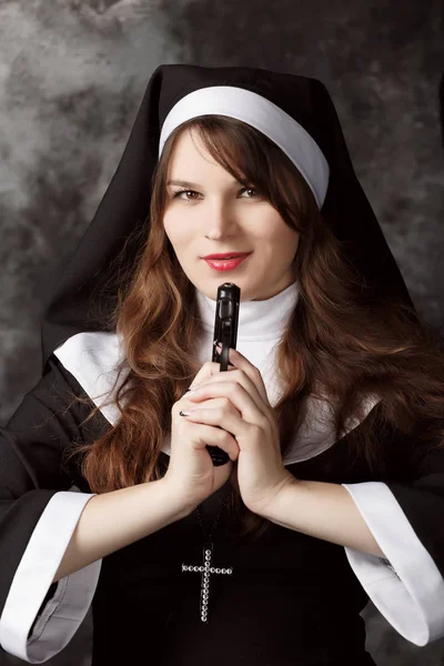 Attractive nun with a gun in his hand on a dark background — Stock Photo, Image