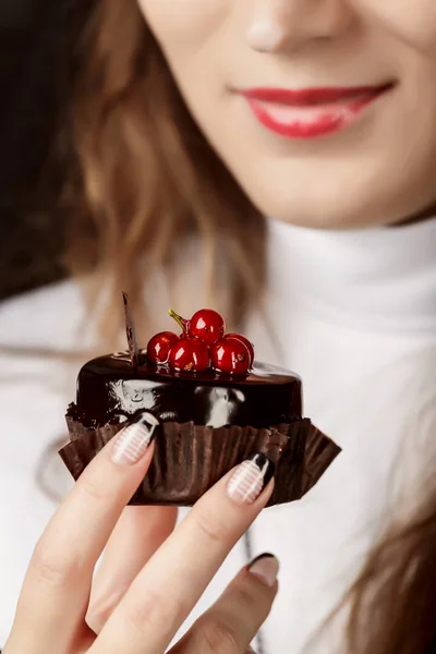 Nahaufnahme einer Frau, die einen Schokoladenkuchen mit roten Beeren in der Hand hält — Stockfoto