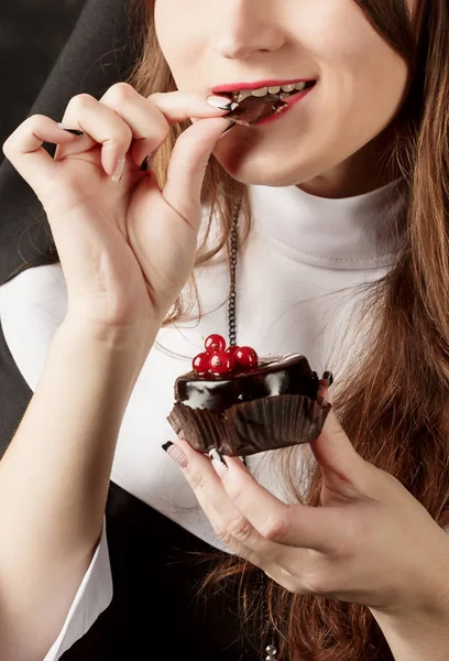 Gros plan d'une femme tenant un gâteau au chocolat avec des baies rouges et mange un morceau de chocolat — Photo