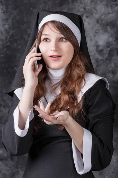 Monja hablando en un teléfono celular sobre un fondo oscuro — Foto de Stock