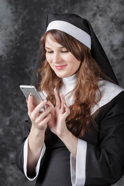 Nun use return a mobile phone on a dark background — Stock Photo, Image