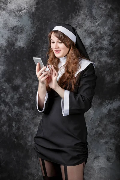 수녀 사용 어두운 배경에 휴대 전화를 반환 — 스톡 사진
