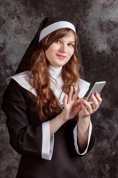 Nun use return a mobile phone on a dark background — Stock Photo, Image