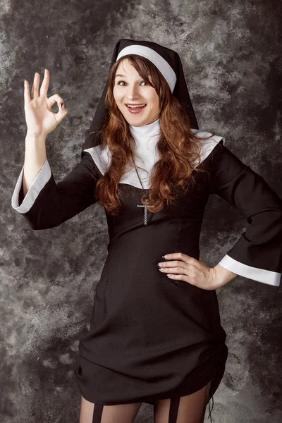 有吸引力的修女在深色背景上显示符号竖起大拇指 ok — 图库照片