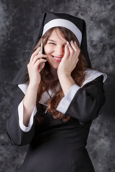 어두운 배경에 휴대 전화에 말하는 수녀 — 스톡 사진