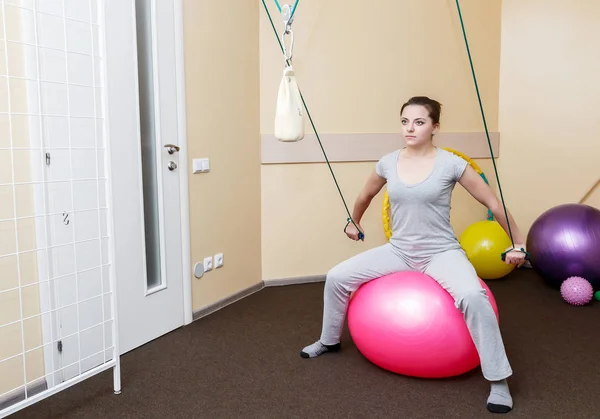 Ung kvinna patienten göra fysiska övningar i en rehabilitering study.young kvinna gör övningar på gym boll. — Stockfoto