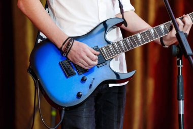 closeup rockstar elektro gitar çalmaya sahnede. Beyaz gömlekli erkek gitarist