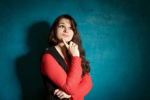 Μελαχρινή νεαρή γυναίκα σε μια ομορφιά μπλούζα και μαύρο σακάκι στέκεται με φόντο έναν τοίχο μπλε και σκέφτεται — Φωτογραφία Αρχείου