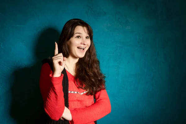 Young brunette woman in a beauty blouse and black jacket standing against the backdrop of a blue wall — Stock Photo, Image