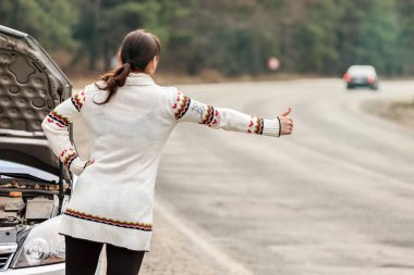 arabasını yol parçalanmışlığın ve Beklemeler yakınındaki duran genç kadın kadar başparmak ve yardımcı olacak araçları durdurun