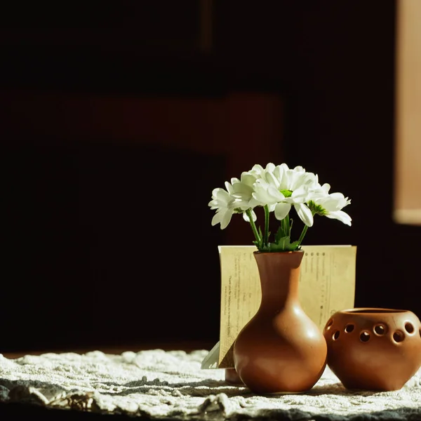 Stillleben. eine braune Tonvase mit Chrysanthemen steht auf einem Tisch mit einer weißen Tischdecke im Speisesaal — Stockfoto