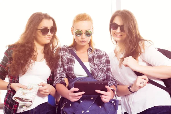 Tři dívky stojí na letišti a při pohledu na tabletu. Tr — Stock fotografie