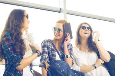 Üç genç kadın ayakta Havaalanı ve gülmek güneş gözlüğü. Arkadaş grubu bir gezi