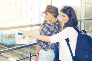 İki genç kız haritaya bakın ve işaret parmağı yön göstermek