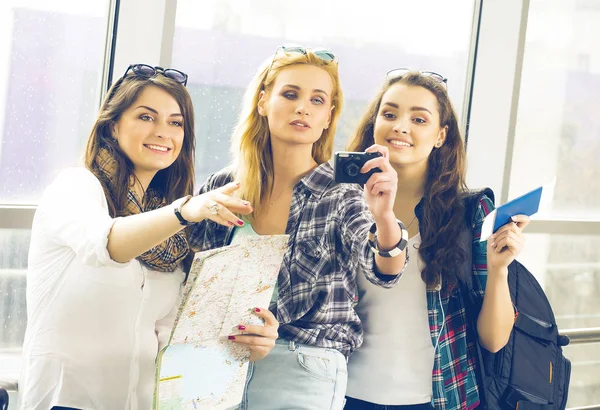 Tři dívky stojí na letišti a při pohledu na tabletu. Výlet s friends.girls dělají selfie — Stock fotografie