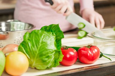 Bir kadın bir salatalık ve sebze bıçakla keser. Genç kadın evde mutfakta yemek. Sağlıklı gıda. Diyet.