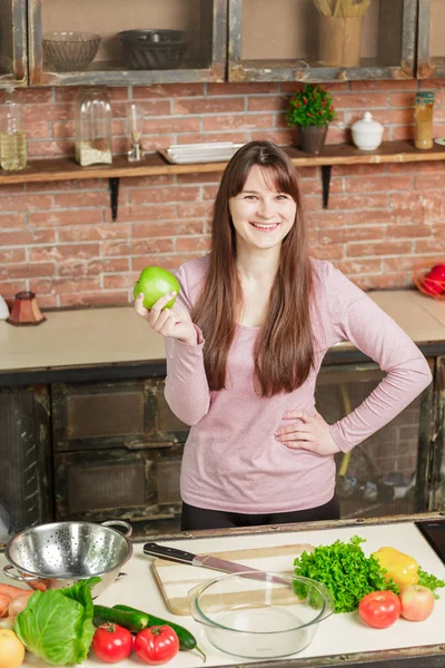 Woman holding a green apple.Young Woman Cooking in the kitchen at home. Healthy Food. Diet.