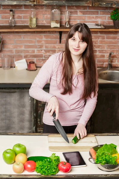 Chica mira la tableta.Mujer joven Cocinando en la cocina en casa. Comida saludable . — Foto de Stock