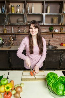 Genç kadın kesme sebze bıçağı kullanarak ve yönetim kurulu pişirme. O mutfakta taze yemek hazırlanıyor.