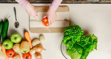 Genç kadın kesme sebze bıçağı kullanarak ve yönetim kurulu pişirme. O mutfakta taze yemek hazırlanıyor.