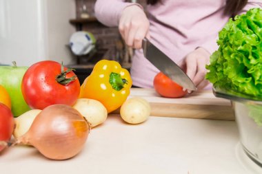 Genç kadın kesme sebze bıçağı kullanarak ve yönetim kurulu pişirme. O mutfakta taze yemek hazırlanıyor.