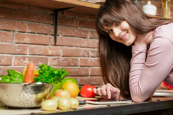 Mujer está haciendo compras en línea por tableta. Ama de casa encontró nueva receta para cocinar en una cocina — Foto de Stock