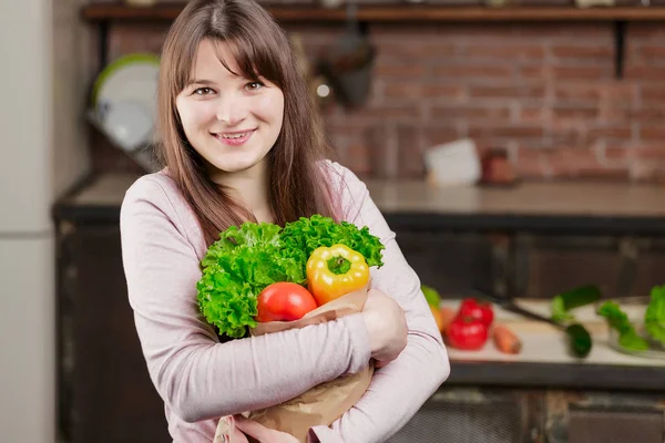 Wanita muda yang bahagia dengan sayuran di tas belanja. Gadis cantik di dapur Memasak makanan sehat. Konsep Diet — Stok Foto