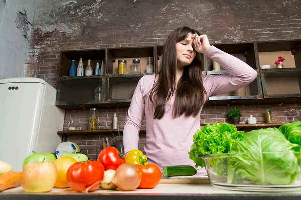 Bir kadın bir salatalık mutfakta bıçakla keser. Salata hazırlanması. Kadın yorgun aşçılar, kafasına tutunur