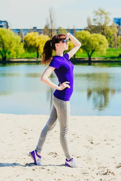 Hermosa joven haciendo ejercicio de fitness en una playa — Foto de Stock