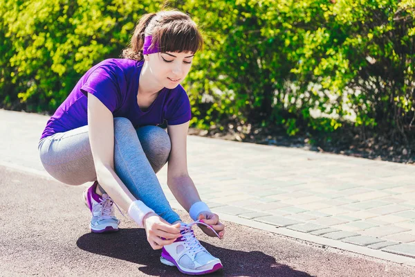 Primo piano di donna allacciatura lacci scarpe. Femmina corridore di fitness sportivo si prepara per correre all'aperto sul sentiero forestale — Foto Stock