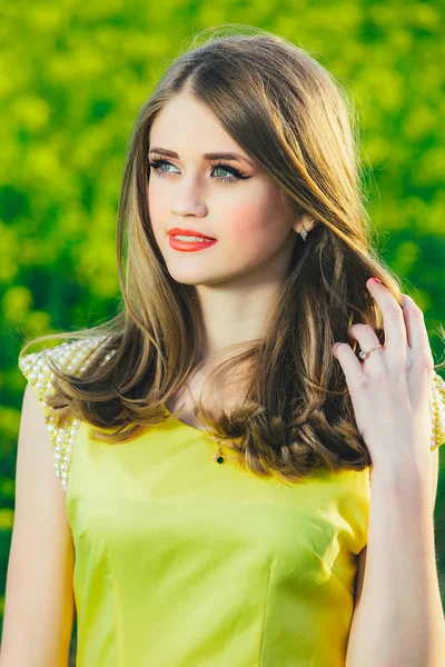 Портрет красивой девочки-подростка в желтом платье на фоне зелени . — стоковое фото