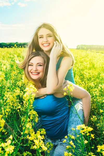 2 krásná dívka v oblasti žluté květy. Máma s dcerou nebo dvě sestry objímání na pozadí pole — Stock fotografie