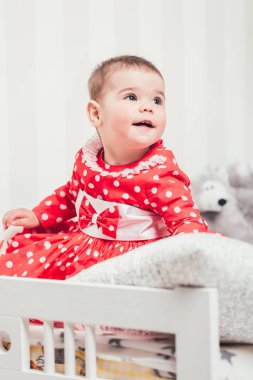 Kırmızı elbiseli bir yaşındaki kız bir oda oturuyor