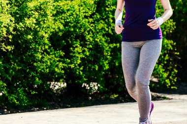 kız mavi tişört içinde yeşil çalılıkları arka karşı çalışır. Spor ve sağlıklı yaşam kavramı.