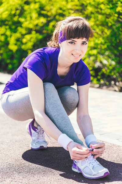 Sport, fitness, people and lifestyle concept - close up of woman tying shoelaces outdoors Stock Picture