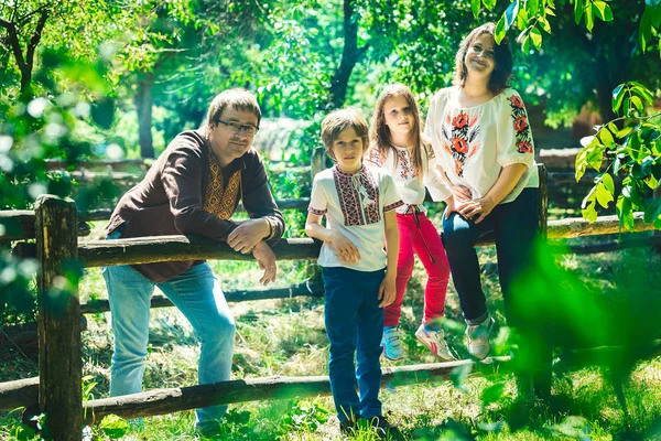 Küçük oğluyla mutlu Ukraynalı aile ve bir kırsal kesimde geleneksel Ukrayna elbiseli kızı park.