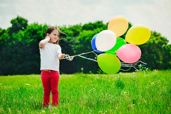 Маленька дівчинка з повітряними кулями в полі — стокове фото