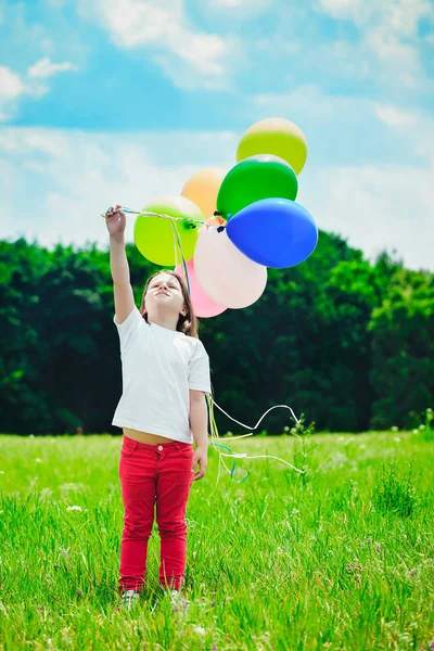 Маленька дівчинка з повітряними кулями в полі — стокове фото
