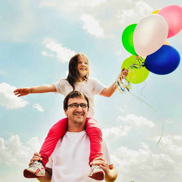 happy family sitting with balloons outdoor on a warm summer day