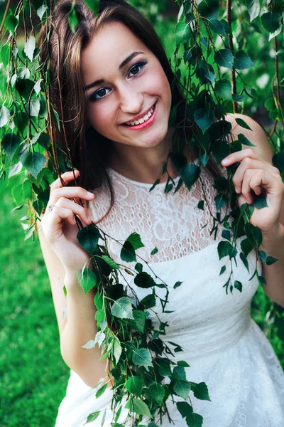 Jeune belle femme brune en robe blanche en branches de bouleau — Photo