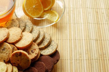 Cam bardak çay bisküvi ve hafif ahşap arka plan üzerinde limon ile. Çay limon ve bisküvi