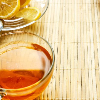 Cam bardak çay bisküvi ve hafif ahşap arka plan üzerinde limon ile. Çay limon ve bisküvi