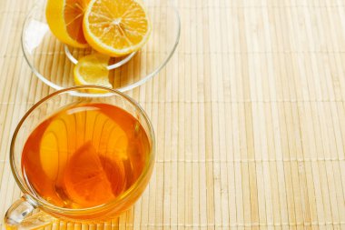 Cam bardak çay bisküvi ve hafif ahşap arka plan üzerinde limon ile. Çay limon ve bisküvi