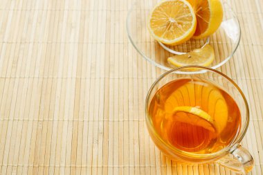 Cam bardak çay bisküvi ve hafif ahşap arka plan üzerinde limon ile. Çay limon ve bisküvi