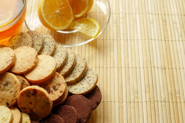 Cam bardak çay bisküvi ve hafif ahşap arka plan üzerinde limon ile. Çay limon ve bisküvi