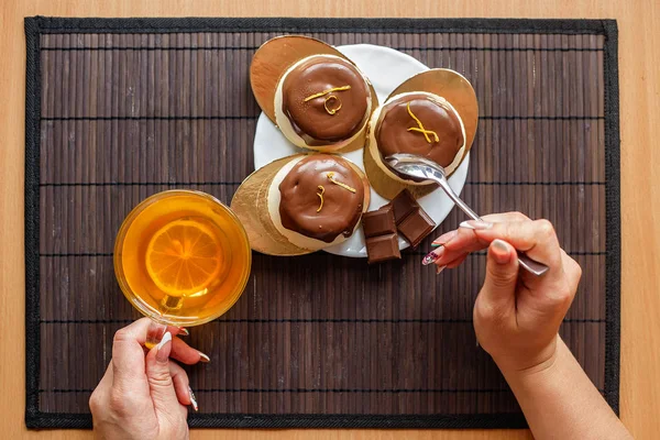 Koyu ahşap arka plan üzerinde çay pasta. Erkek bir arka plan kek ve bir bardak çay üzerinde eller.